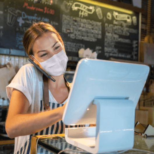 Image d'une hotesse de caisse avec un masque sur le visage, lié au covid en train de prendre une commande dans un restaurant